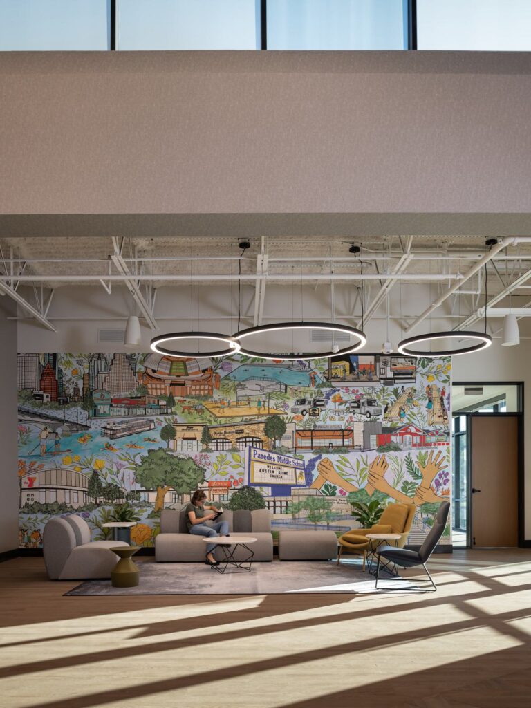 A modern church lobby and lounge features a vibrant mural, stylish furniture, and large windows, creating a cozy and inviting atmosphere.