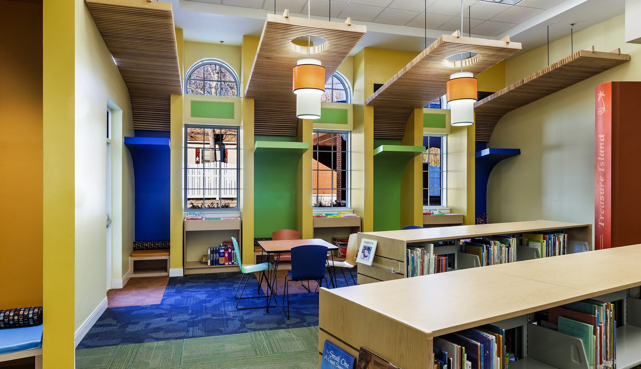 A vibrant library space featuring colorful walls, cozy reading nooks, and modern shelving, inviting creativity and relaxation.