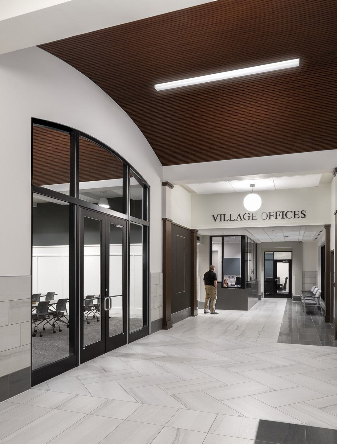 A modern office lobby with a spacious layout, glass doors, a reception area, and a stylish ceiling, featuring a neutral color palette.