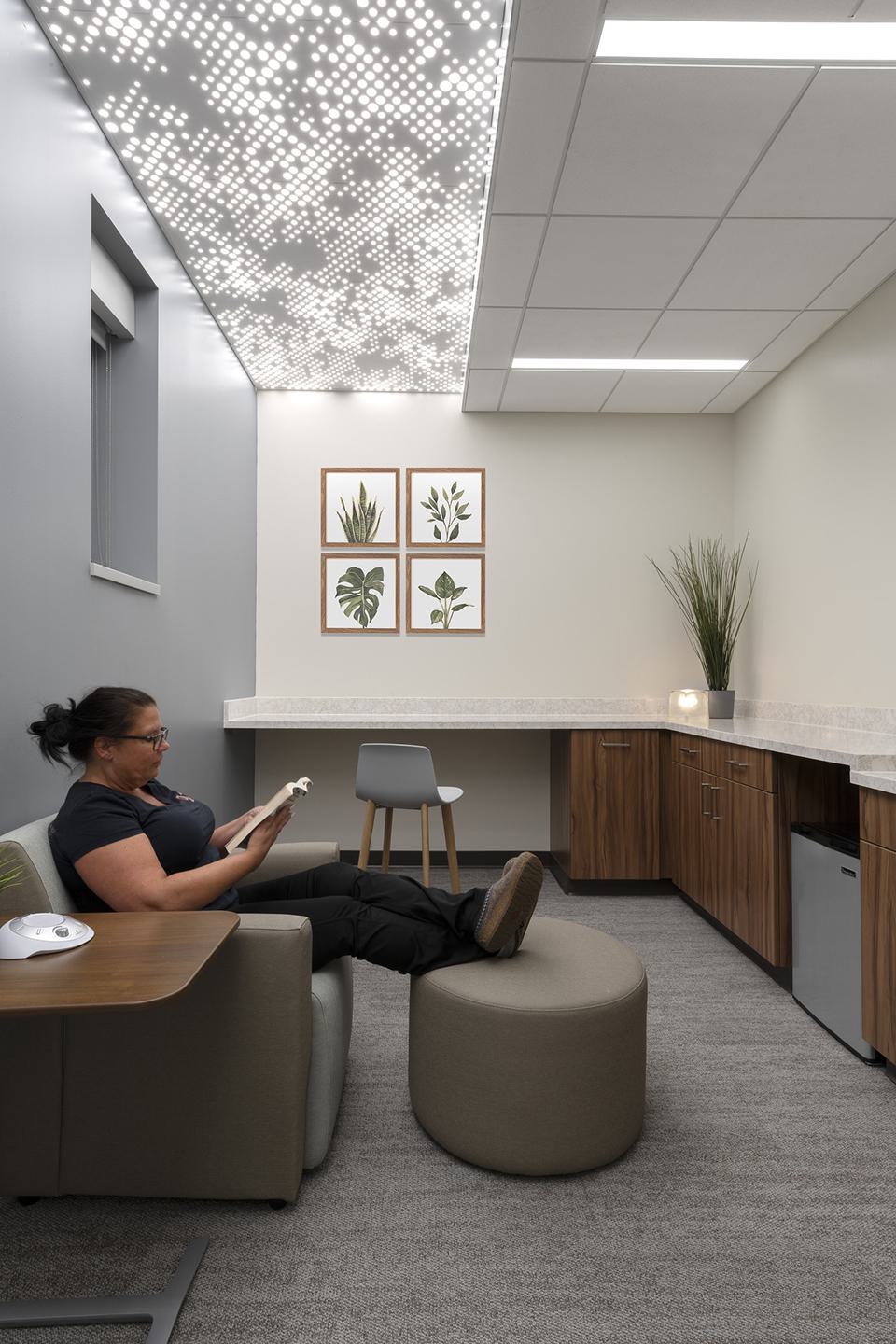 A cozy, modern relaxation space features a person reading, stylish furnishings, plant artwork, and a unique ceiling design.