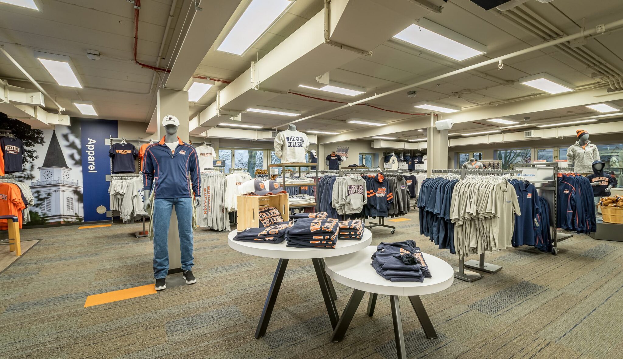A spacious store features apparel displays, including shirts and sweatshirts, with mannequins showcasing various outfits.