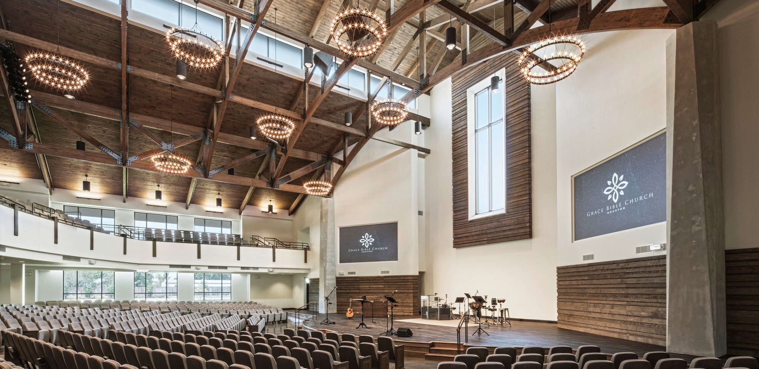 A spacious, modern auditorium featuring high wooden beams, elegant lighting, and rows of seating, designed for gatherings and events.