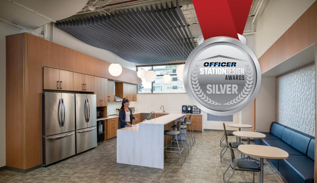 A modern kitchen space with wood cabinetry, sleek appliances, an island, and cozy seating, featuring a design award medal for excellence.