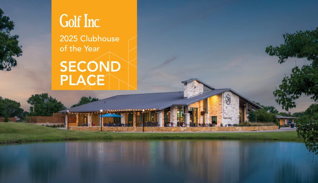 Jersey Meadow Golf Clubhouse, designed by FGM Architects (FGMA) at dusk overlooking a serene lake. Stringed lights brighten up the outdoor patio, and beautiful stone masonry covers the facade. The clubhouse won 2nd place for Golf Inc.'s 2025 Clubhouse of the Year Award.
