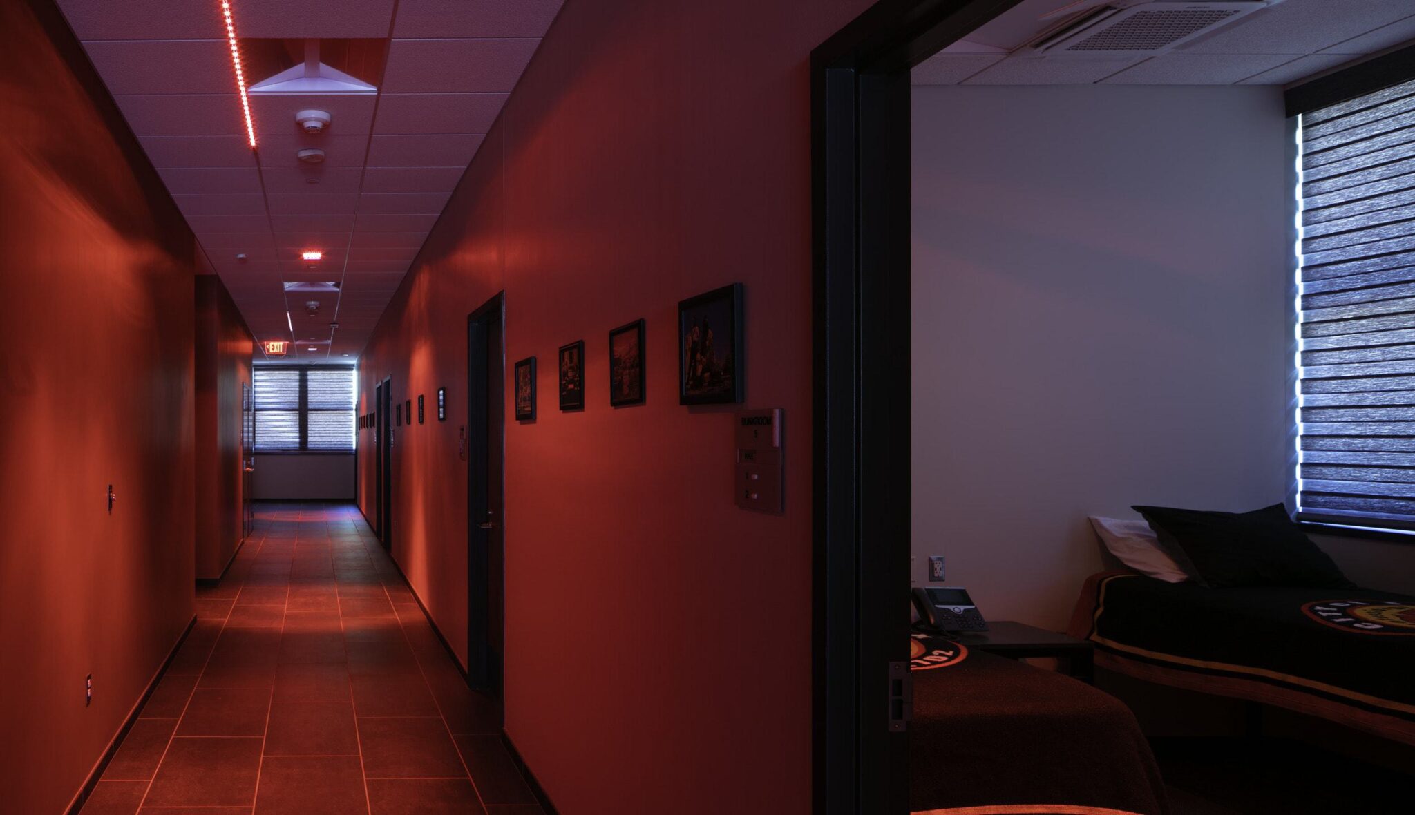 A dimly lit hallway features sleek walls, doorways to rooms, and framed artwork, creating a calm and inviting atmosphere.