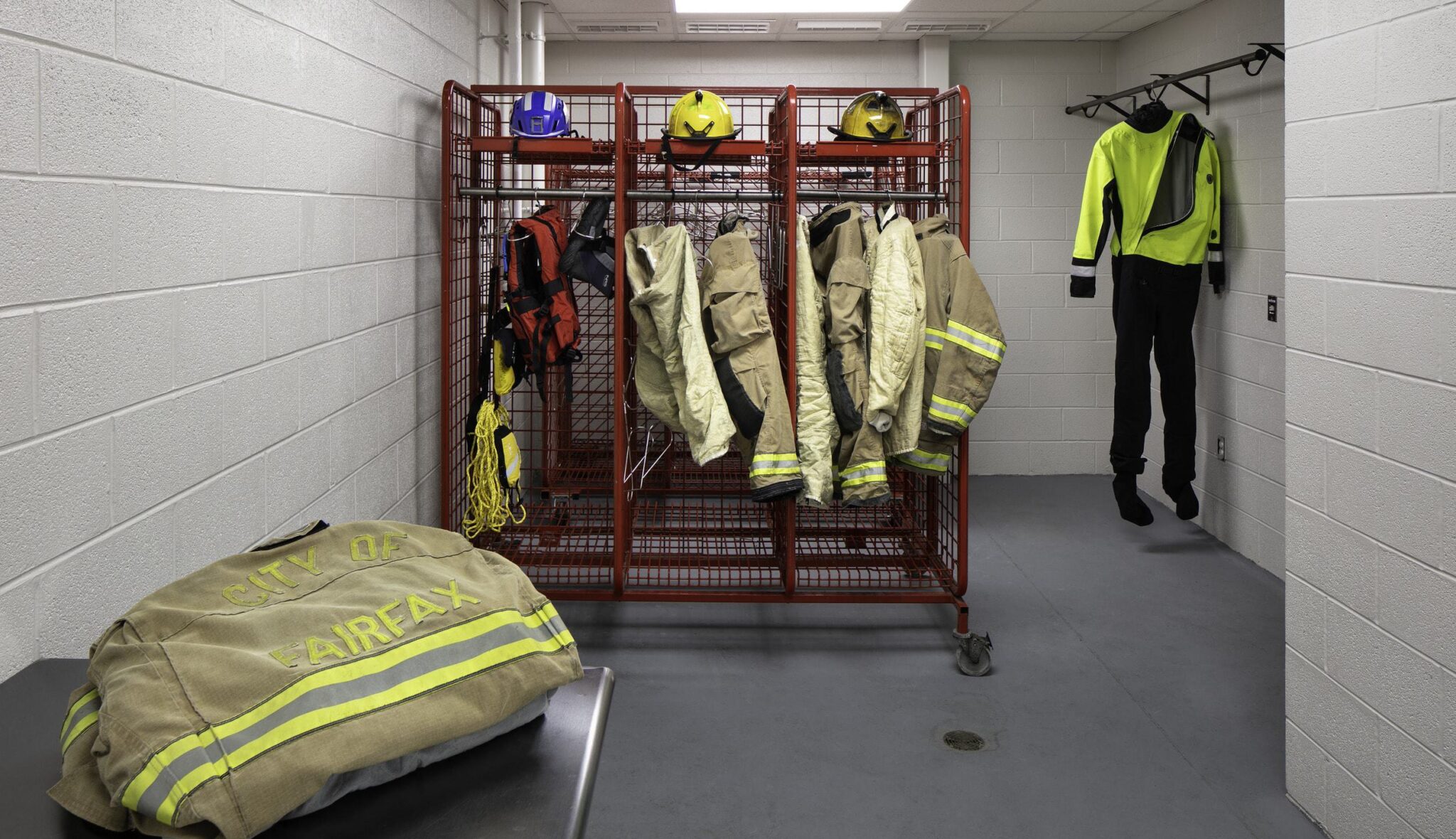 A locker room displays fire gear, helmets, and safety suits, emphasizing preparedness and safety for emergency responders.