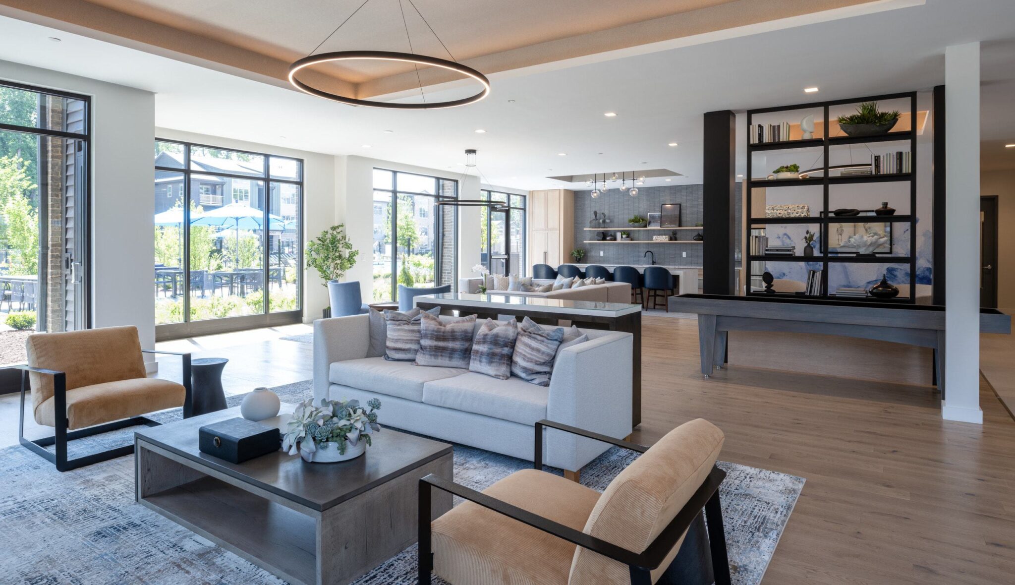 A stylish, spacious common area features large windows, modern furniture, and a cozy decorative touch, creating a bright, inviting atmosphere.