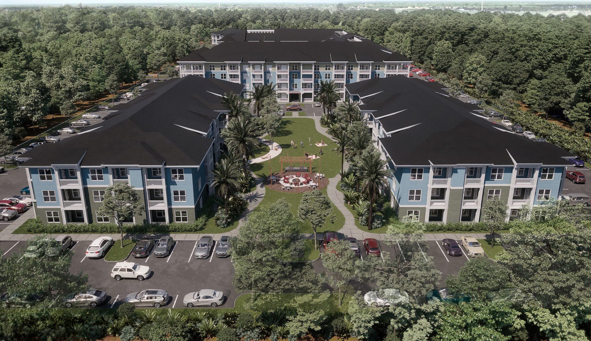 Aerial view of a residential complex surrounded by greenery, featuring multiple buildings, parking spaces, and a landscaped courtyard.
