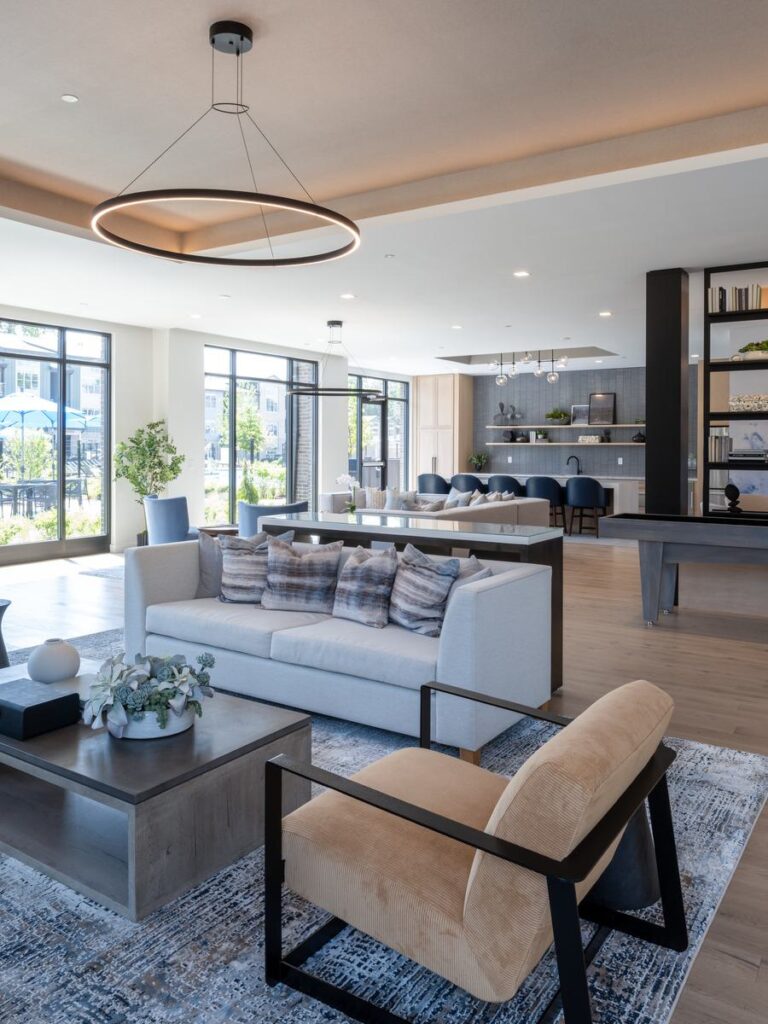 A modern, stylish lounge features a cozy sofa, chic armchair, and large windows, creating a bright and inviting atmosphere.
