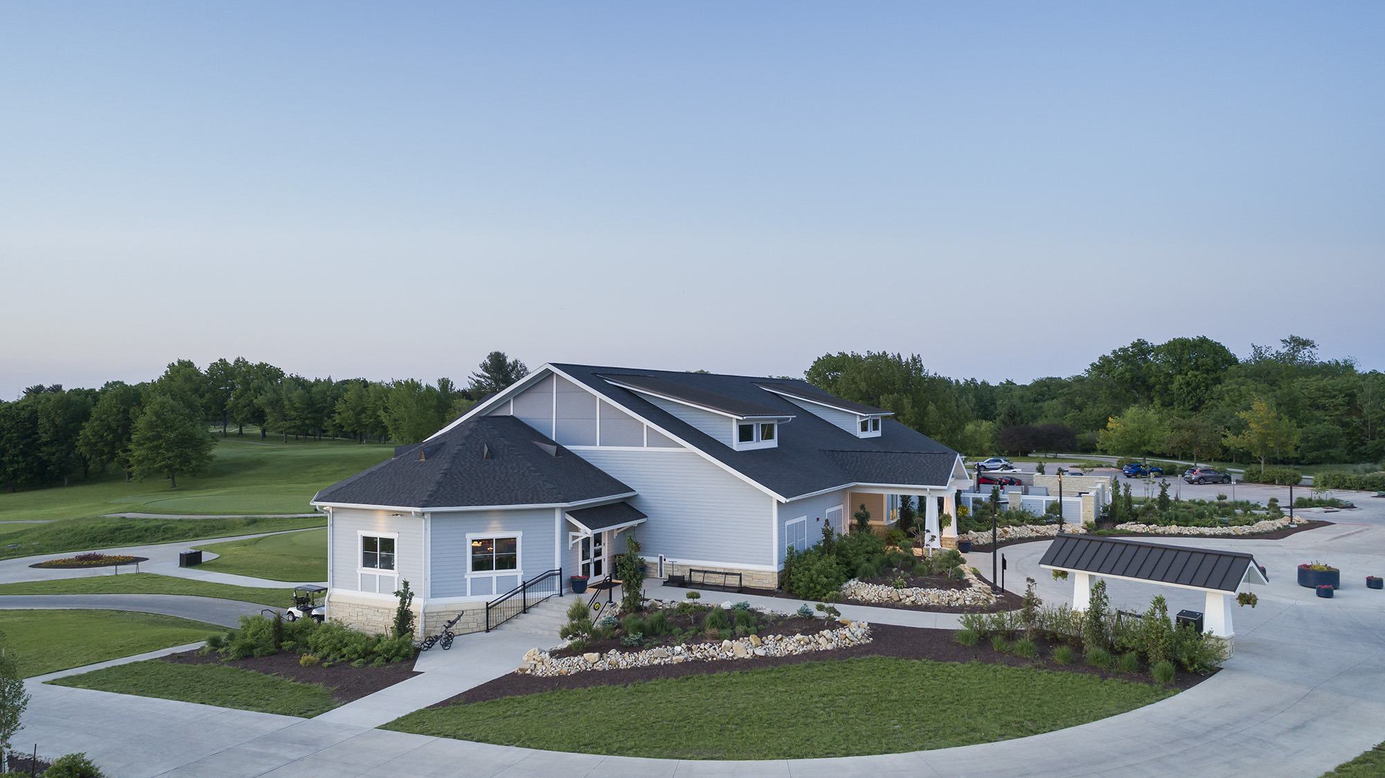 A modern building surrounded by well-maintained landscaping, with green lawns and trees in the background, creating a serene atmosphere.
