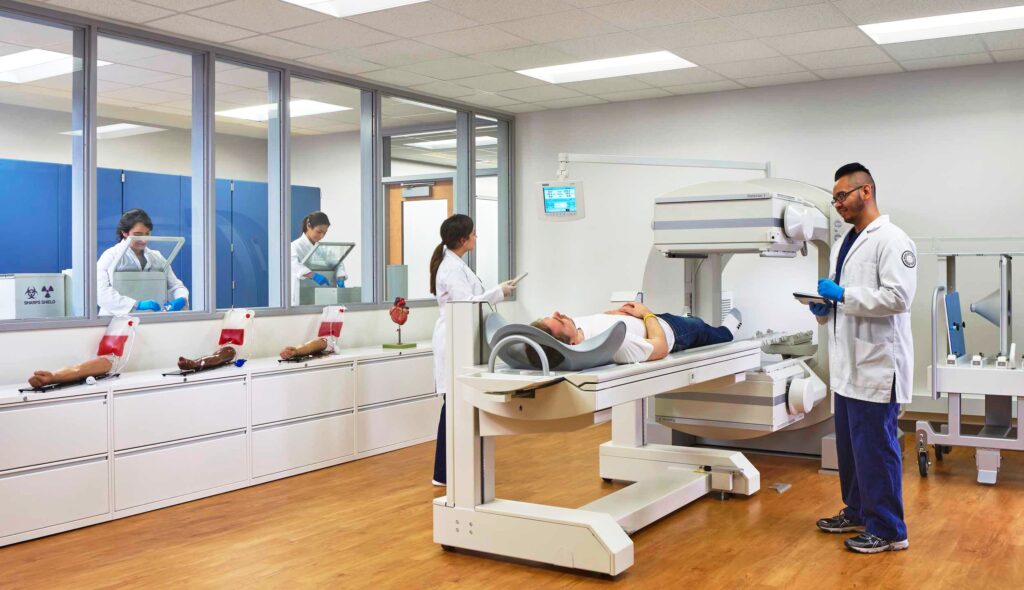 Medical professionals conduct tests in a clinical setting, with a patient lying on equipment and others monitoring from an observation area.