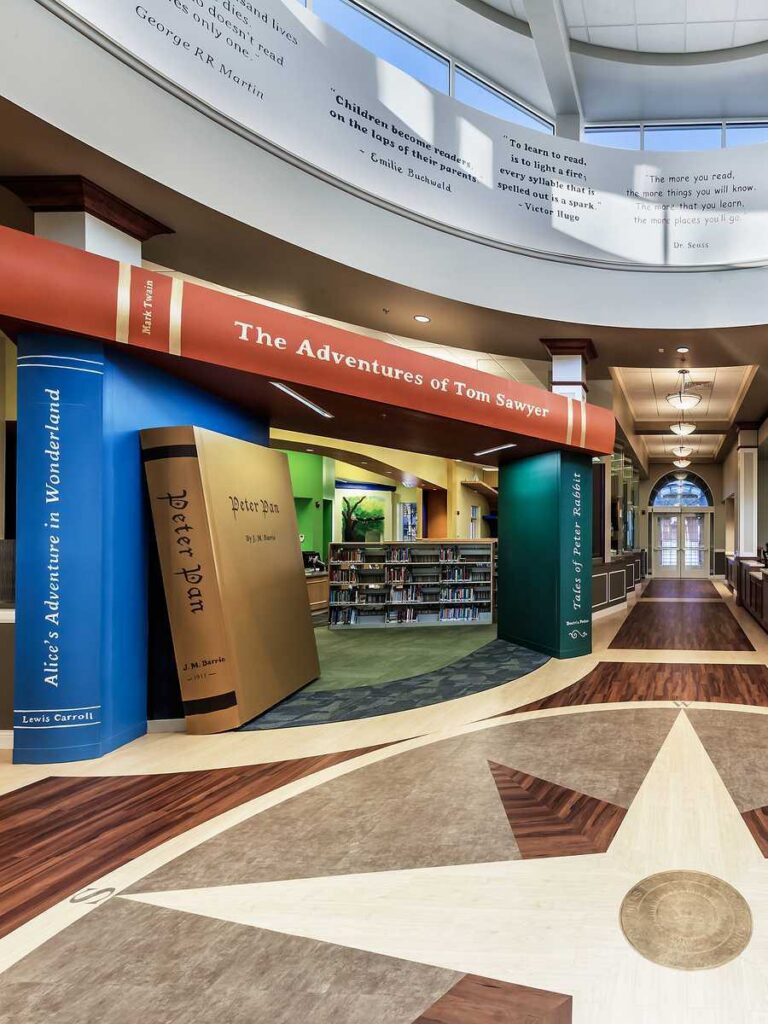 A library’s entrance features oversized book sculptures, highlighting classics like “The Adventures of Tom Sawyer” in a welcoming atmosphere.